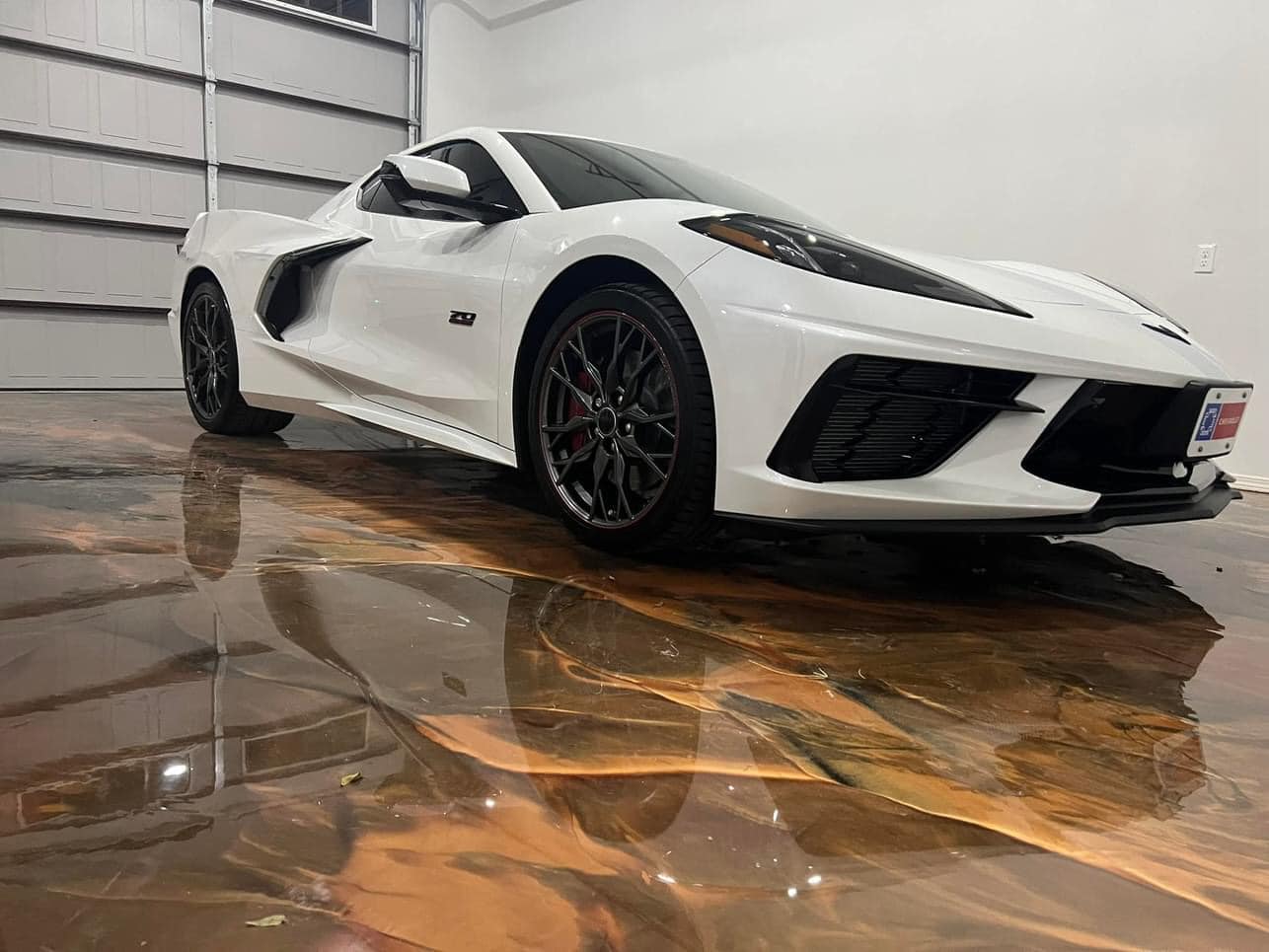 A white Corvette mirrored in a mirror-gloss copper metallic epoxy garage floor.